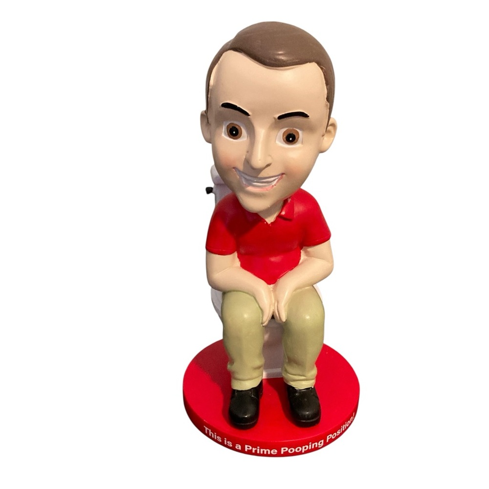 Bobble head sitting on the toilet